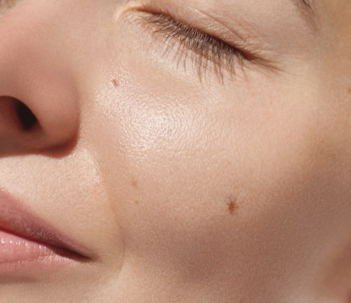 Gros plan d’un visage aux yeux fermés, peau lumineuse et apaisée